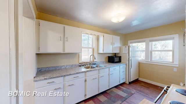 kitchen featuring baseboards, light countertops, white appliances, white cabinetry, and a sink