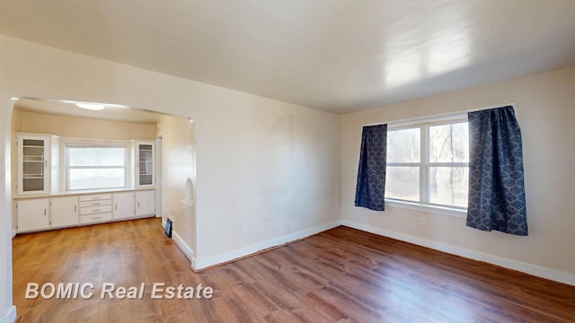 spare room with baseboards and wood finished floors