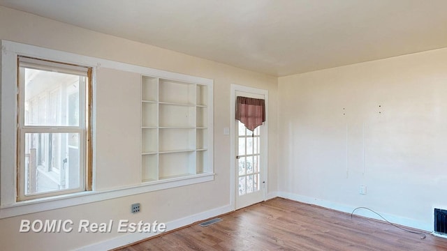 unfurnished room with visible vents, baseboards, and wood finished floors