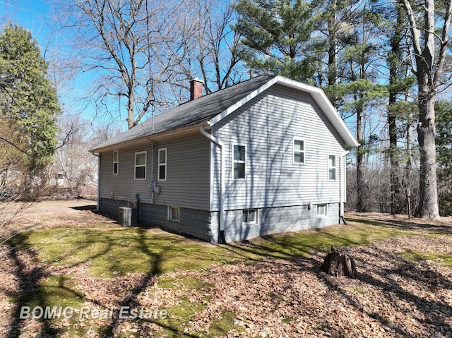 view of property exterior featuring a yard, central AC unit, and a chimney