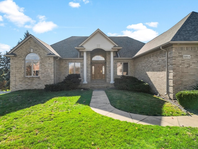 view of front facade with a front lawn, brick siding, and a shingled roof