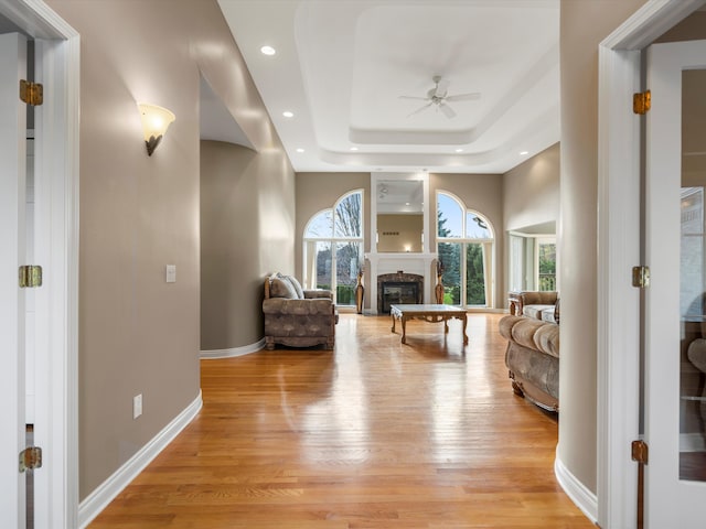 sitting room featuring a ceiling fan, a glass covered fireplace, recessed lighting, light wood finished floors, and baseboards