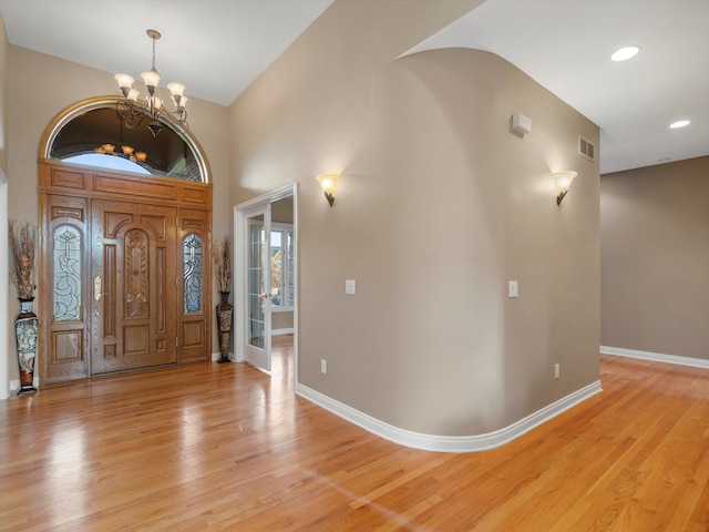 foyer entrance featuring visible vents, baseboards, a notable chandelier, and light wood finished floors