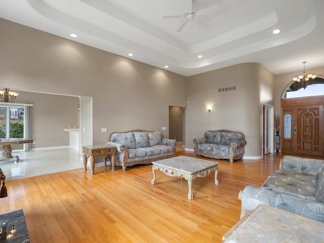 living area with visible vents, a high ceiling, a tray ceiling, and wood finished floors