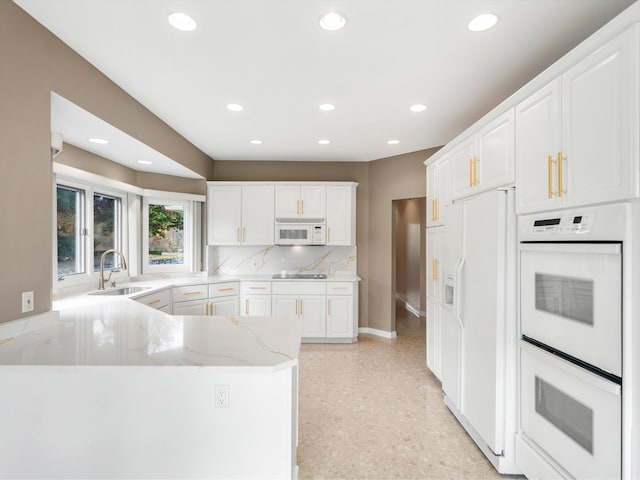 kitchen with a sink, white cabinetry, recessed lighting, white appliances, and light stone countertops