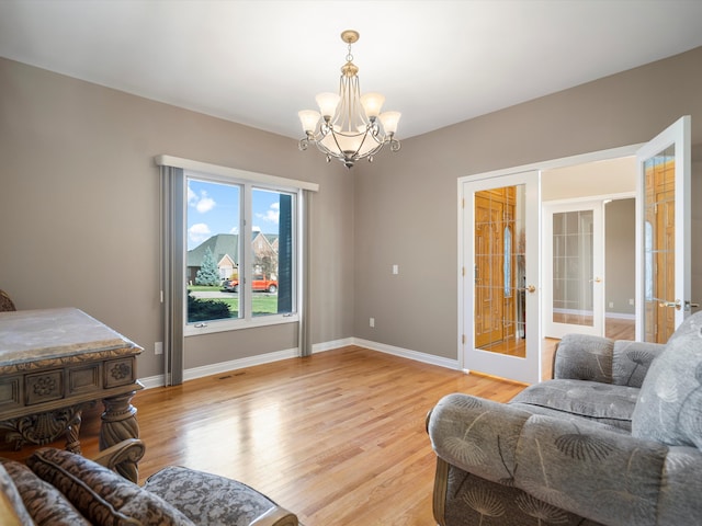 living area featuring a chandelier, french doors, baseboards, and light wood-style floors