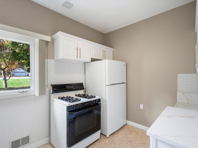 kitchen with range with gas cooktop, light stone countertops, visible vents, and freestanding refrigerator