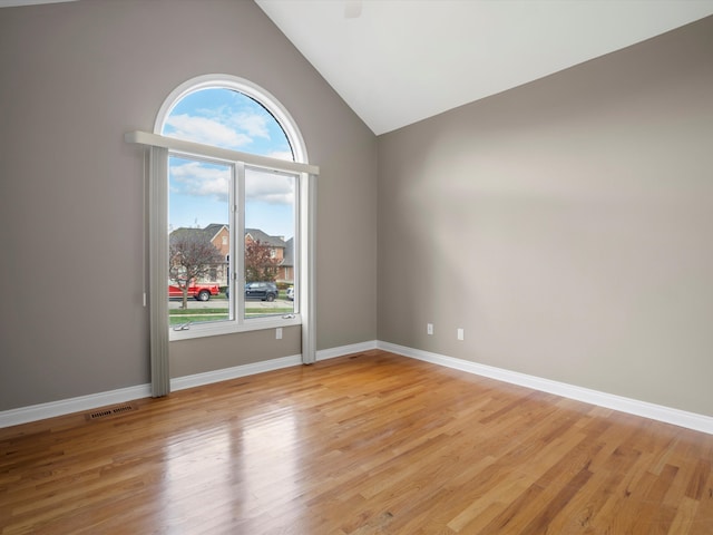 spare room with visible vents, baseboards, high vaulted ceiling, and light wood-style flooring