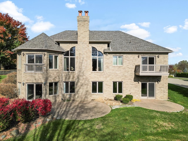 back of house featuring brick siding, a shingled roof, a chimney, a yard, and a patio