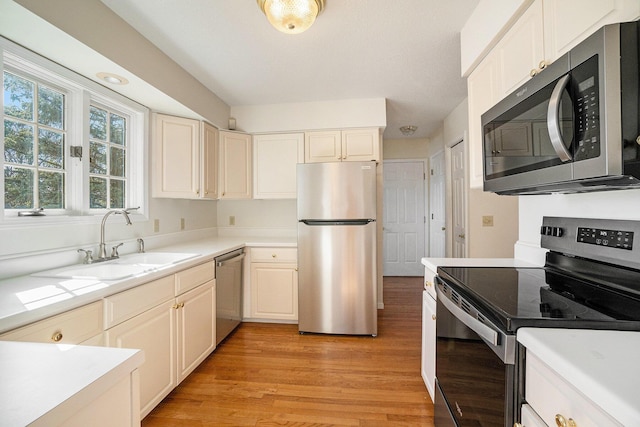 kitchen featuring a sink, light wood-style floors, appliances with stainless steel finishes, and light countertops