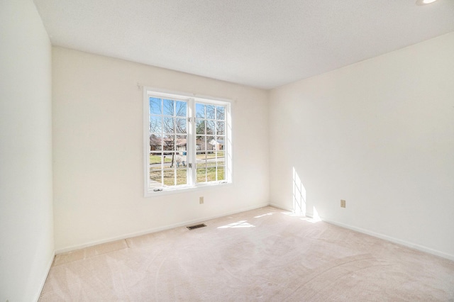 carpeted empty room with visible vents and baseboards