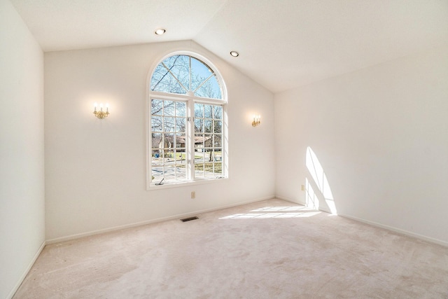 carpeted empty room with lofted ceiling, baseboards, and visible vents