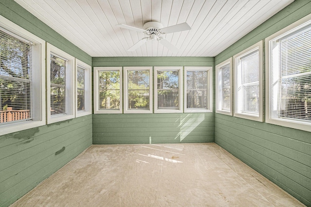 unfurnished sunroom featuring wood ceiling, plenty of natural light, and a ceiling fan