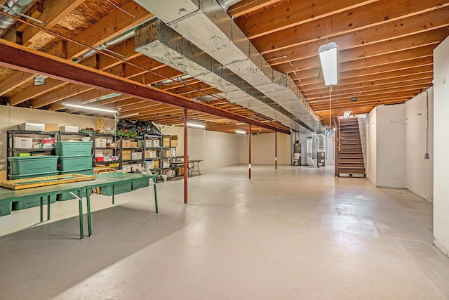 unfinished basement featuring gas water heater and stairs