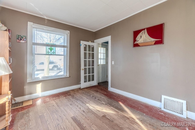 interior space with visible vents, wood finished floors, baseboards, and ornamental molding