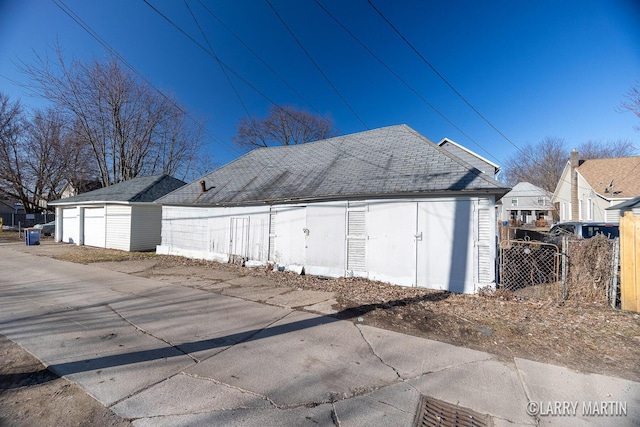 exterior space featuring an outdoor structure and a shingled roof