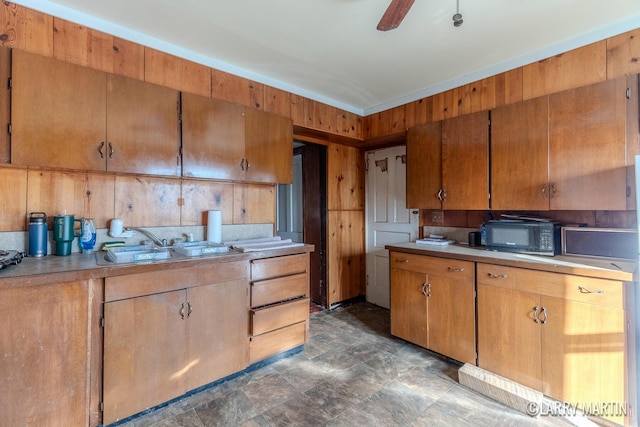 kitchen with brown cabinets, a ceiling fan, light countertops, and black microwave