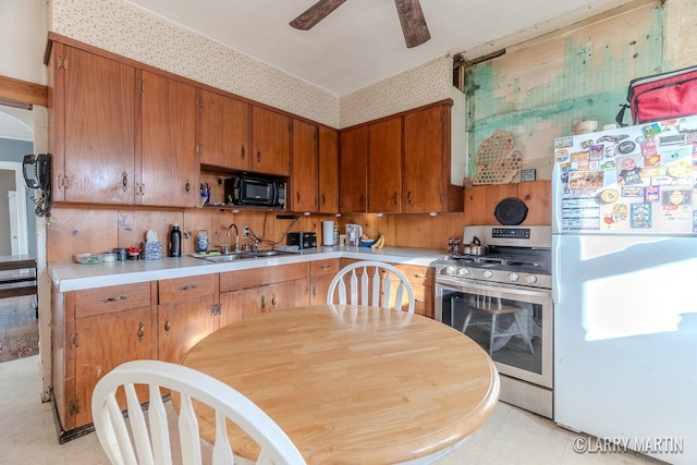 kitchen featuring black microwave, light countertops, freestanding refrigerator, stainless steel gas range, and a sink