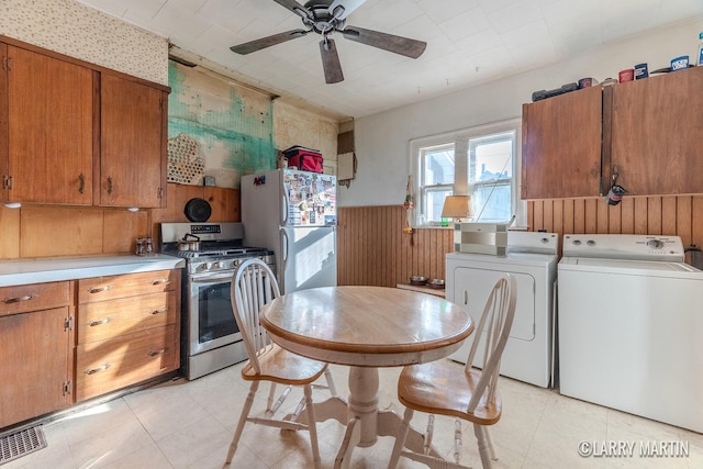 kitchen featuring visible vents, freestanding refrigerator, brown cabinetry, gas stove, and separate washer and dryer