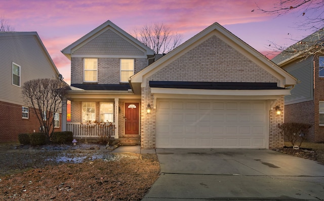 traditional-style house featuring brick siding, covered porch, concrete driveway, and a garage