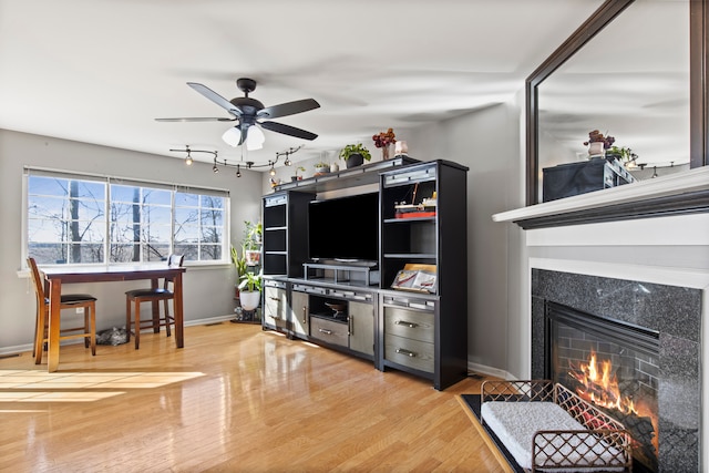 living room with ceiling fan, baseboards, wood finished floors, and a tile fireplace