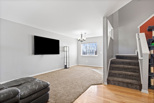 carpeted living area with stairway, a notable chandelier, and baseboards