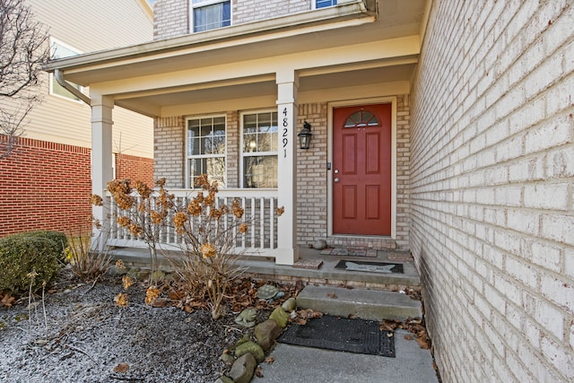 entrance to property featuring covered porch and brick siding