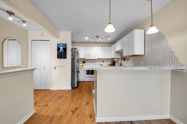 kitchen featuring tasteful backsplash, light countertops, a peninsula, white cabinets, and white appliances