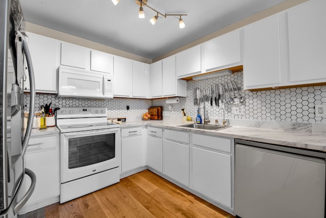 kitchen with light wood finished floors, backsplash, stainless steel appliances, white cabinetry, and a sink