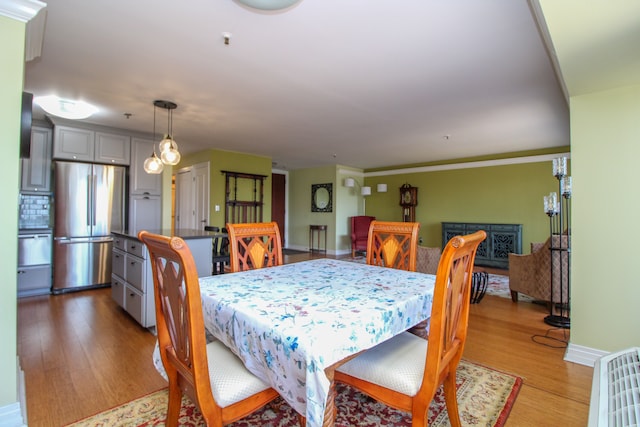 dining area featuring a fireplace, baseboards, and light wood-style floors