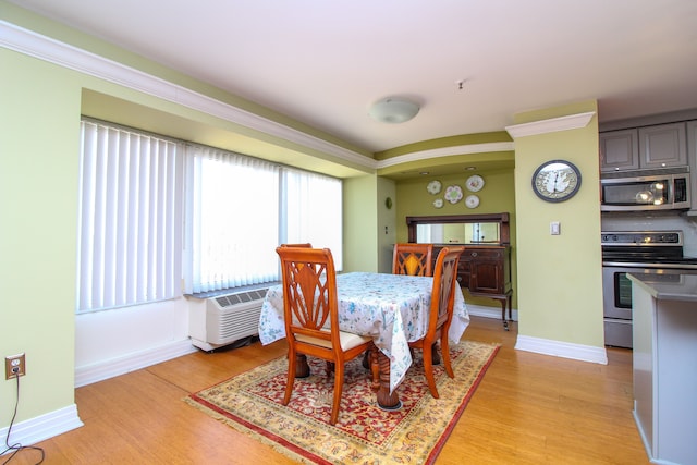 dining area featuring cooling unit, light wood-style floors, and baseboards