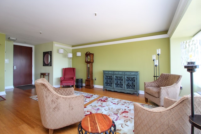 living area featuring crown molding, wood finished floors, and baseboards