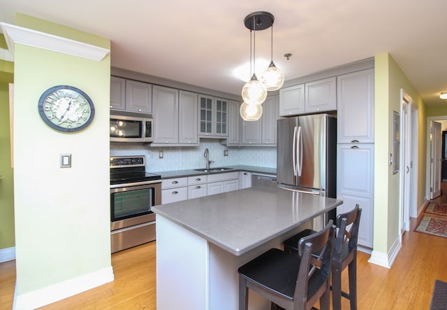 kitchen with light wood finished floors, gray cabinets, appliances with stainless steel finishes, and a sink