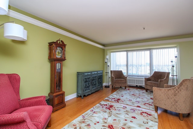 living area with baseboards, radiator, wood finished floors, and crown molding