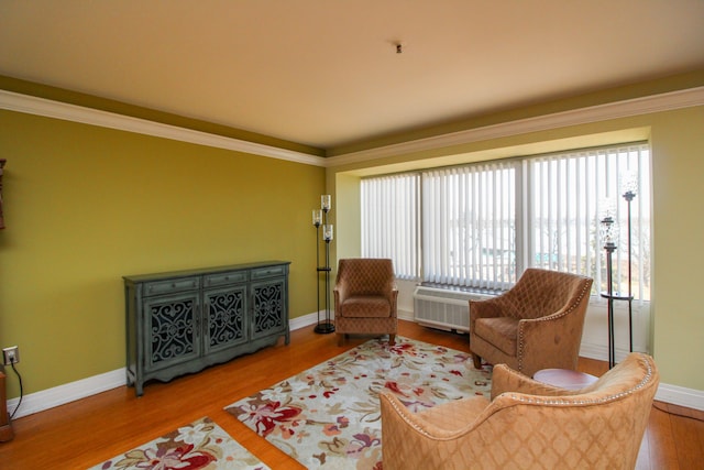 living area with wood finished floors, baseboards, and ornamental molding