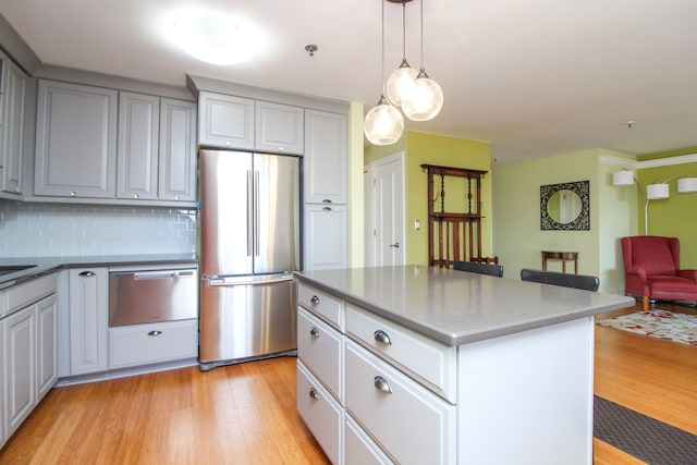 kitchen featuring a warming drawer, open floor plan, freestanding refrigerator, light wood finished floors, and decorative backsplash