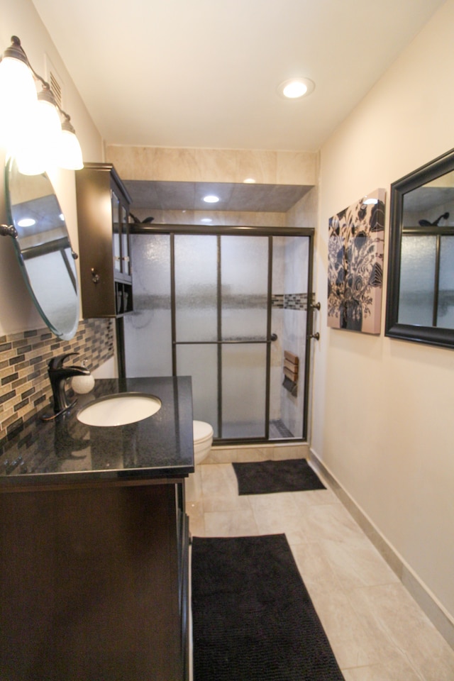 bathroom with toilet, a stall shower, backsplash, baseboards, and vanity