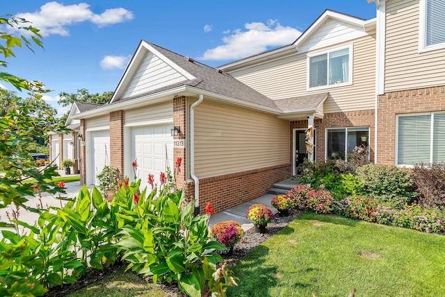 view of front of home featuring an attached garage, a shingled roof, a front lawn, concrete driveway, and brick siding