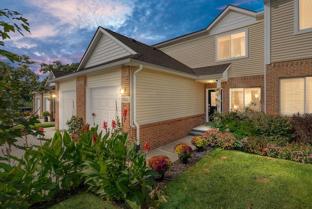 exterior space with a front yard, roof with shingles, concrete driveway, a garage, and brick siding