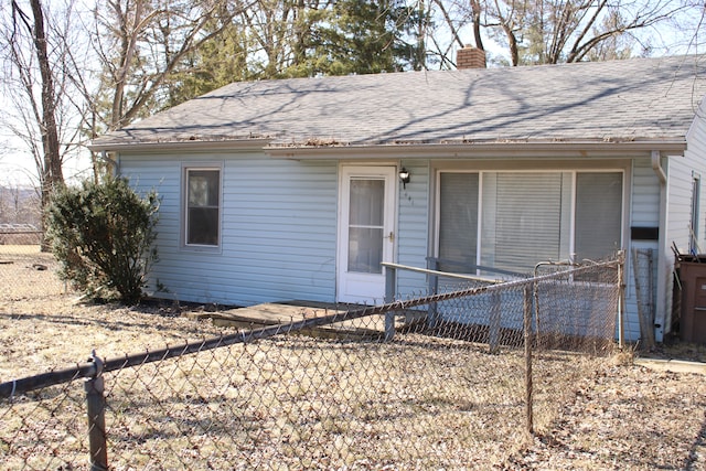 view of front of house featuring roof with shingles, fence private yard, and a chimney