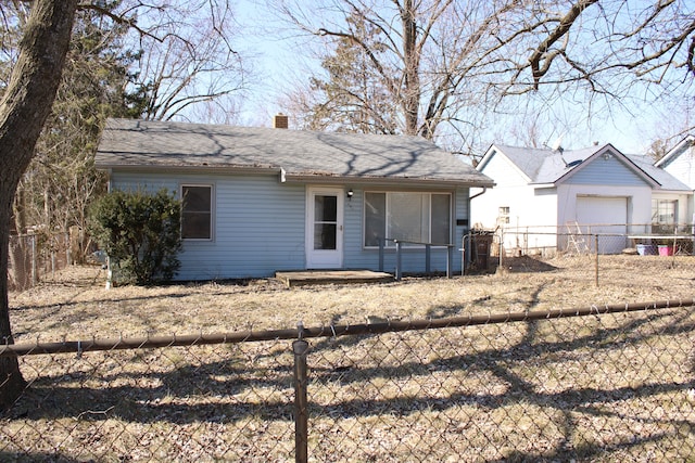 rear view of house featuring a chimney, a fenced backyard, and roof with shingles