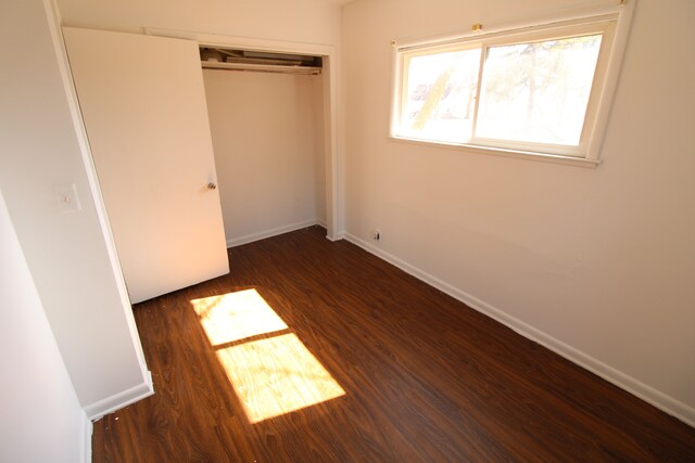 unfurnished bedroom with wood finished floors, a closet, and baseboards