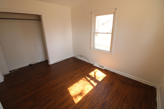 unfurnished bedroom featuring dark wood finished floors, visible vents, and baseboards