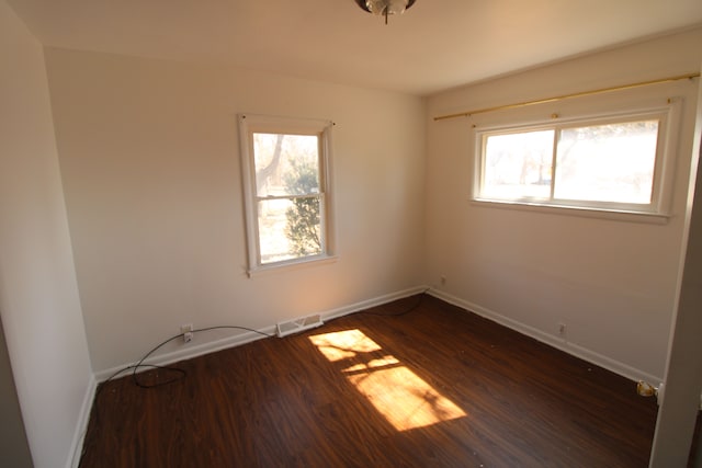 unfurnished room with visible vents, baseboards, and dark wood-type flooring