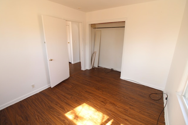 unfurnished bedroom with a closet, baseboards, and dark wood finished floors