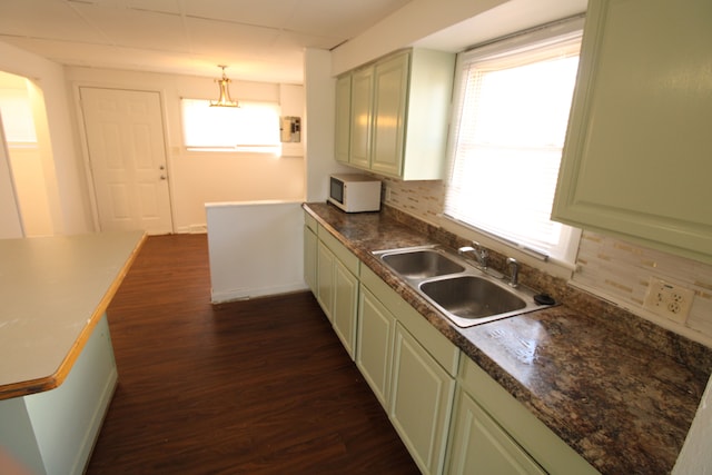 kitchen featuring a sink, tasteful backsplash, dark countertops, white microwave, and dark wood-style flooring