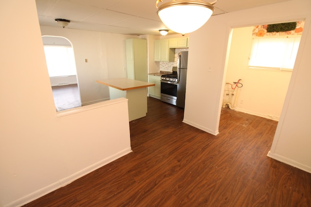 kitchen with tasteful backsplash, arched walkways, appliances with stainless steel finishes, baseboards, and dark wood-style flooring