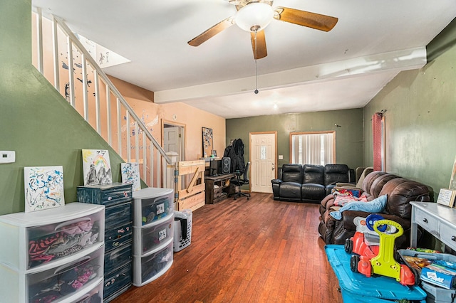 living area with beam ceiling, stairway, a ceiling fan, and wood finished floors