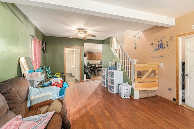 living area featuring ceiling fan, baseboards, wood finished floors, and stairs