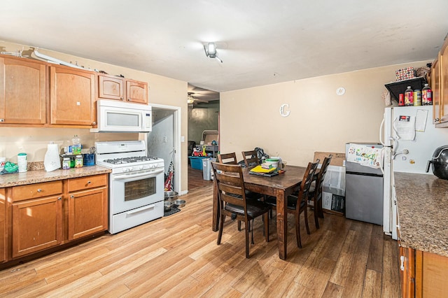 kitchen featuring light wood-type flooring, white appliances, brown cabinets, and light stone countertops